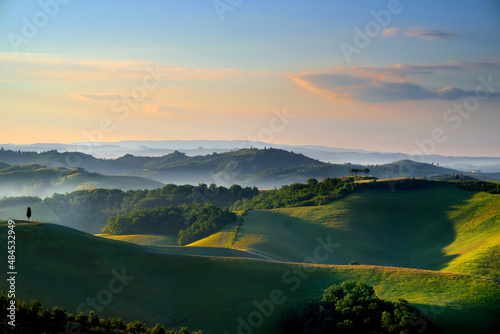 Stunning morning view of fields and farmlands with small villages on the horizon. Rural landscape of rolling hills, curved roads and cypresses of Tuscany, Italy.