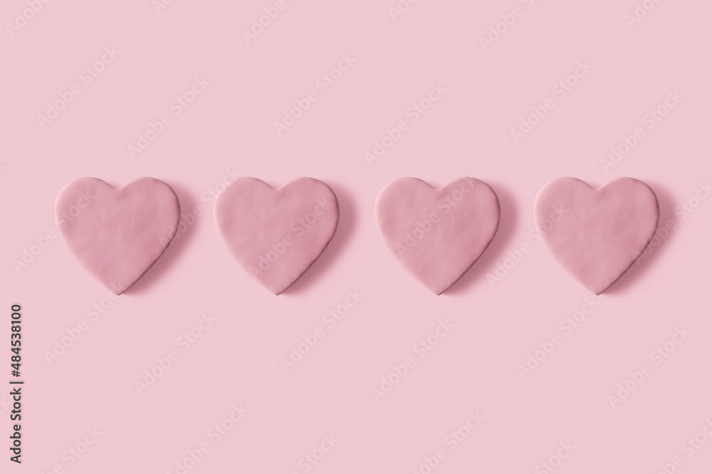 Lined up love hearts made of pink plasticine on pastel background