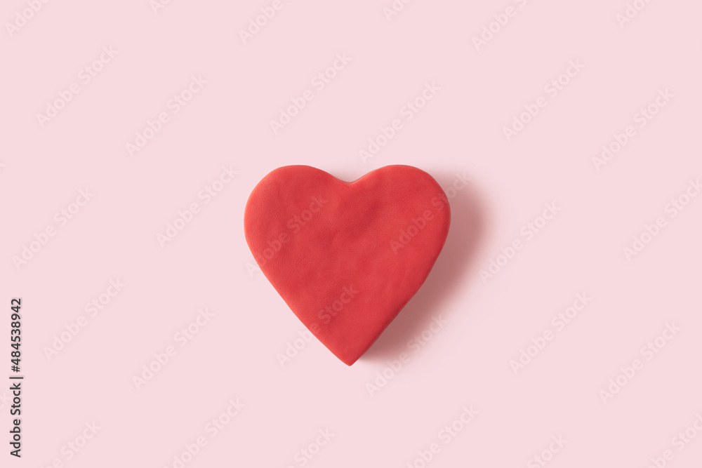 Heart figure handmade from red plasticine on pastel pink background, copy space. Valentines Day card