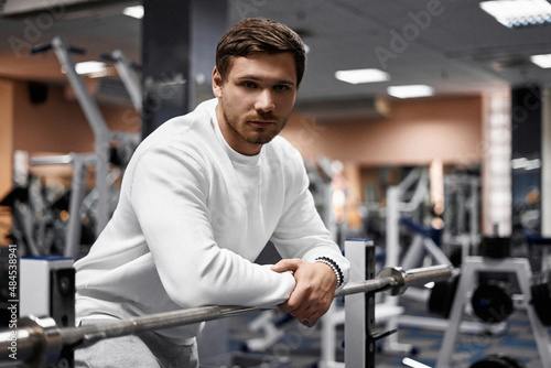 Portrait of handsome young muscular caucasian man posing in gym, Confident fitness trainer in modern sport club interior advertising healthy lifestyle