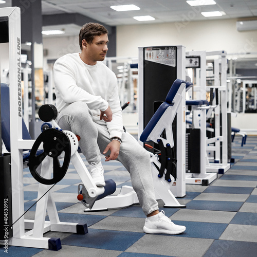 Portrait of handsome young muscular caucasian man posing in gym, Confident fitness trainer in modern sport club interior advertising healthy lifestyle