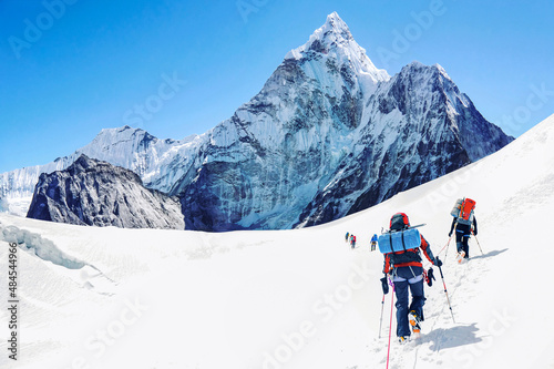 Group of equipped mountaineers crossing snowfield on a way to summit. On a background view on Mount Ama Dablam in Nepal