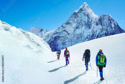 Group of climbers reaches the summit of mountain peak enjoying the landscape view.