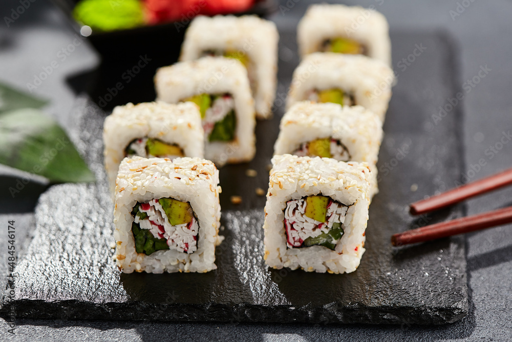 Maki sushi on dark stone table. Sushi roll california in sesame. Maki