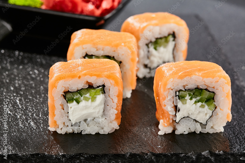Maki sushi on dark stone table. Philadelphia maki with salmon. Sushi
