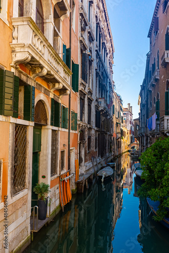 Traditional Venice cityscape with narrow canal, moored boats and ancients colorful buildings on banks of canal, Italy