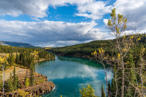 Fototapeta Naklejka Na Ścianę i Meble -  View of Miles Canyon in Whitehorse, Canada during September in fall with yellow colored trees. Amazing turquoise water flowing along Yukon River. 