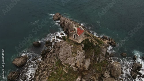 Aerial bird's eye shot of Christian Church of Holy Sunday on small island Katic in Petrovac, Montenegro on a cloudy day. Locals and tourist visit by boat. photo