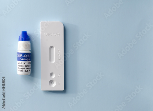 a rapid coronavirus test for covid-19 at home. Test strip and reagent to test the sample on a blue background. space for text