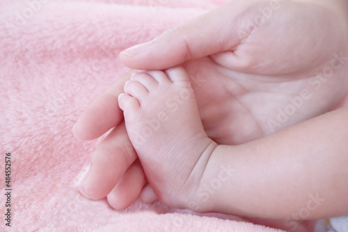 Feet of a newborn baby on white blanket in the hands of parents. Mom and her child. Maternity, family, birth concept. Copy space for your text.