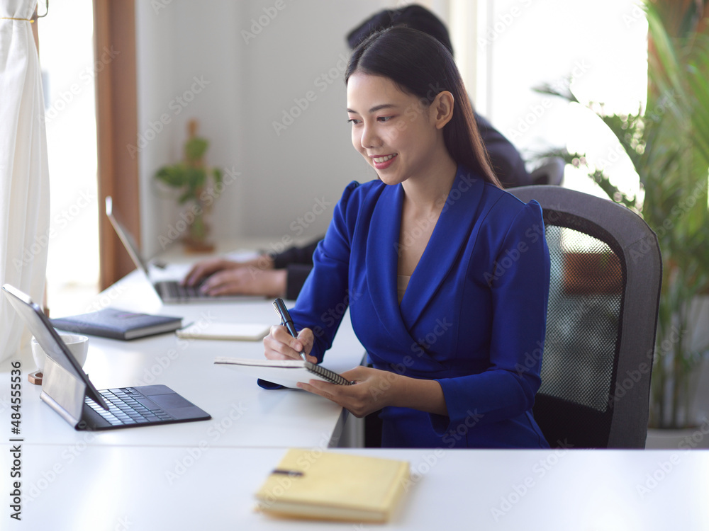 Businesswoman looking at the tablet screen, taking note on desk. Businesswoman looking at the tablet screen, taking note on desk.