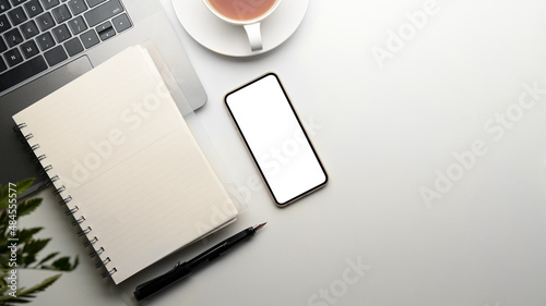 Modern office desk with empty notebook page, smartphone white screen