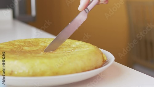 Man cutting a Spanish omelet and serving it on a plate