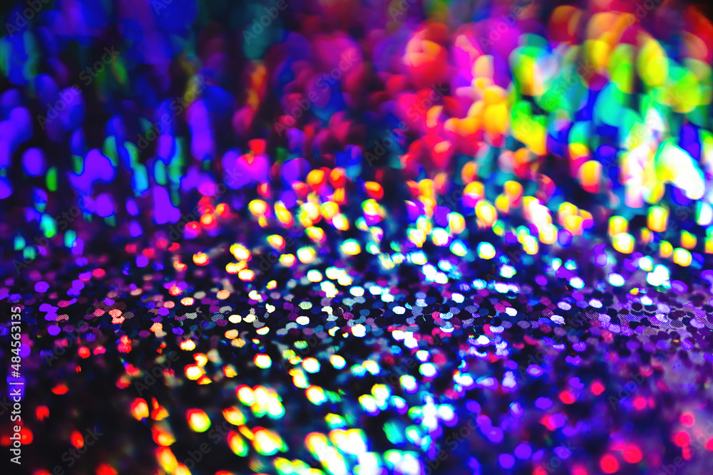 Blurred Neon rainbow glittering lights with glow effect abstract background. Defocused festive twinkle lights bokeh. Modern purple, blue, pink, green dark 80s, 90s design