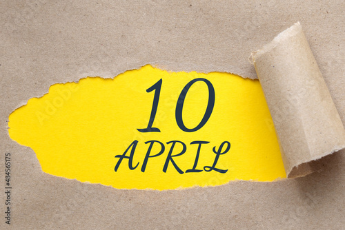 April 10. 10th day of the month, calendar date.Hole in paper with edges torn off. Yellow background is visible through ragged hole.Spring month, day of the year concept photo