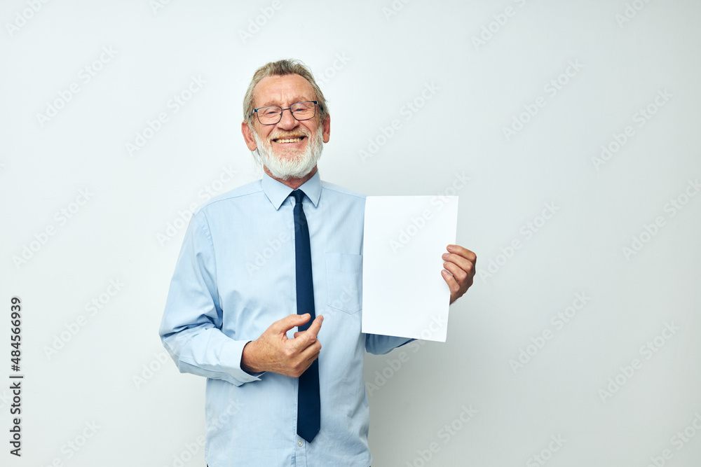 Portrait of happy senior man holding documents with a sheet of paper light background Portrait of happy senior man holding documents with a sheet of paper light background