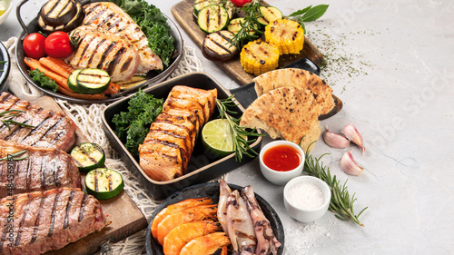 Grilled fish, seafood and meat assortment on light background.