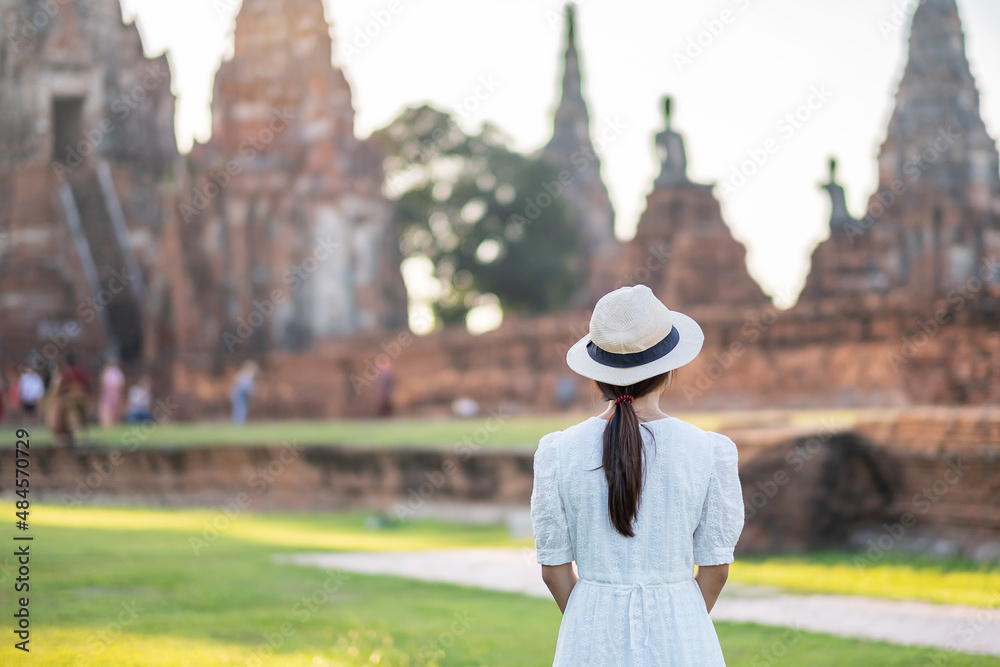 Tourist Woman in white dress visiting to ancient stupa in Wat Chaiwatthanaram temple in Ayutthaya Historical Park, summer, Asia and Thailand travel concept