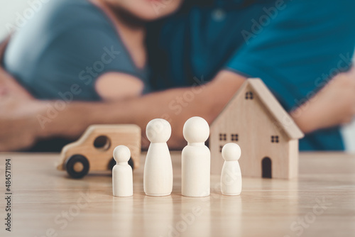Wooden peg dolls  wooden house  and car with a Hugging man and woman couple. planning  saving family   health care and insurance  family mental health  international day of families.