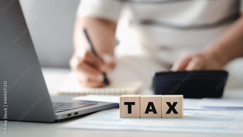 Woman is calculating annual tax with calculator and filling form of Individual Income Tax Return. Season to pay Tax and Budget planning concept. - obrazy, fototapety, plakaty 