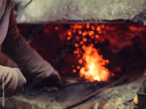 Fototapeta Crop forger burning metal in furnace