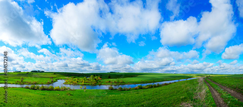 Spring panoramic landscape with river and green fields