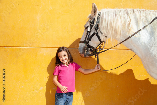 Simpática niña mellada sujetando caballo blanco photo