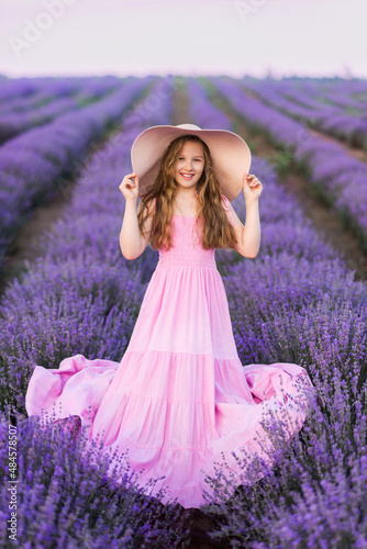 Girls with long hair in a lavender field . A girl In a long pink dress and hat