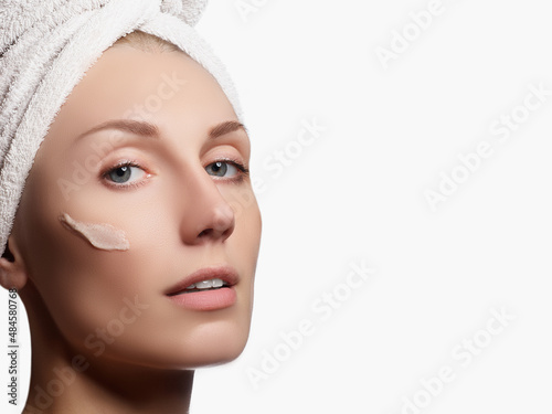 Beauty portrait of a young woman with beautiful healthy person, studio shot attractive girl on a white background, causing a scrub on face. Peeling face. Beautiful girl in a towel on her head