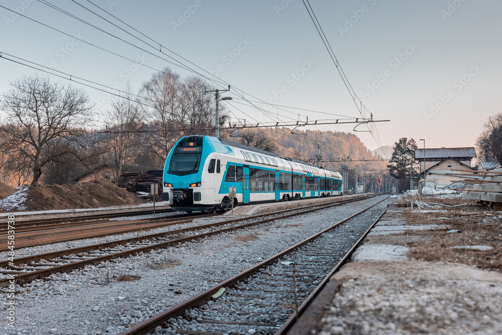 Modern slovenian double decker commuter train is just leaving the rural station of Podnart. Cold and early afternoon in northern Slovenia.
