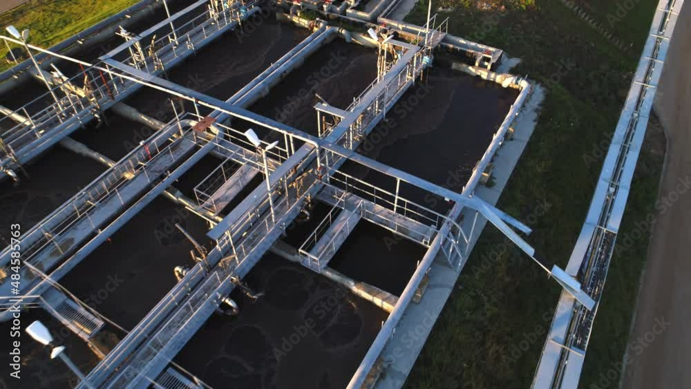 Processed swirling waste water in large reservoirs with bridges and pipelines at sewage treatment plant at sunset aerial view Processed swirling waste water in large reservoirs with bridges and pipelines at sewage treatment plant at sunset aerial view