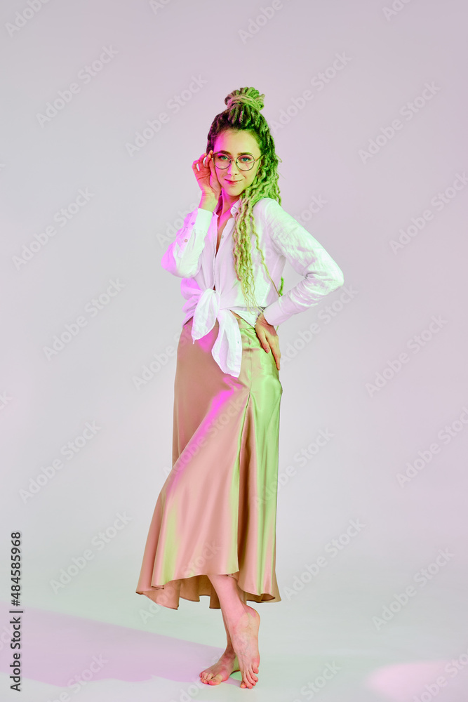 Full length portrait of a woman in linen shirt and chiffon skirt touching the bow of glasses Full length portrait of a woman in linen shirt and chiffon skirt touching the bow of glasses