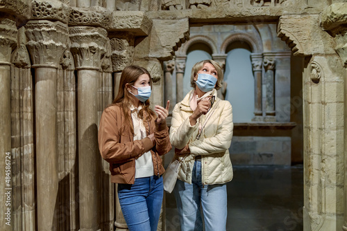 Attentive tween girl with senior woman exploring art museum