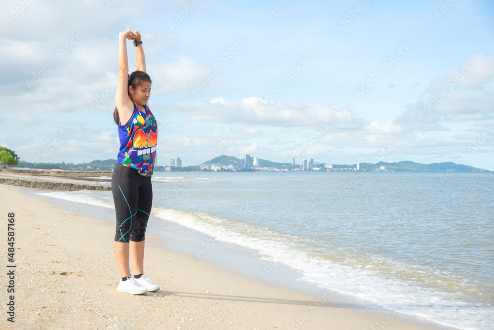 Healthy woman Asian runner people workout fitness nature is doing stretches on the beach.Healthy Concept