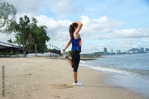 Healthy woman Asian runner people workout fitness nature is doing stretches on the beach.Healthy Concept