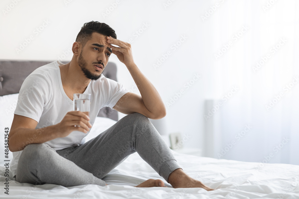 Hangover Concept. Sick Arab Guy Holding Glass Of Water And Touching Head Hangover Concept. Sick Arab Guy Holding Glass Of Water And Touching Head
