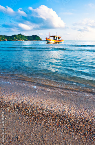 A view of the sea surf on a sandy beach with a ship in the distance