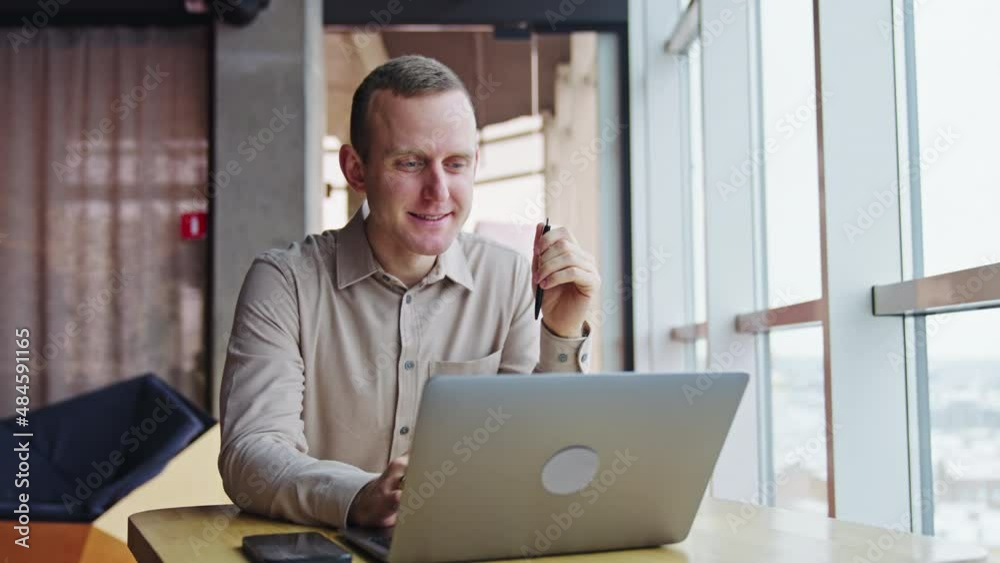 Middle aged man sitting at the computer and smiling broadly. Pleasant working atmosphere in a light office. Middle aged man sitting at the computer and smiling broadly. Pleasant working atmosphere in a light office.