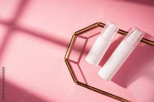 Fotografía Plastic white bottles with pump for cream or lotion on glass plate for product presentation