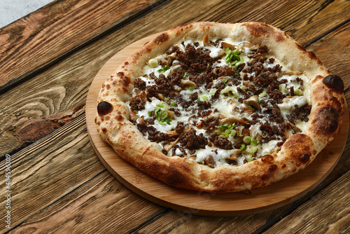 Delicious homemade pizza with mozzarella, mushrooms, beef and chicken. Wooden background, selective focus.