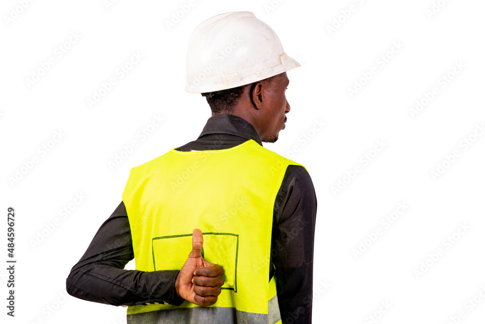 young man construction engineer showing thumb up behind back. young man construction engineer showing thumb up behind back.