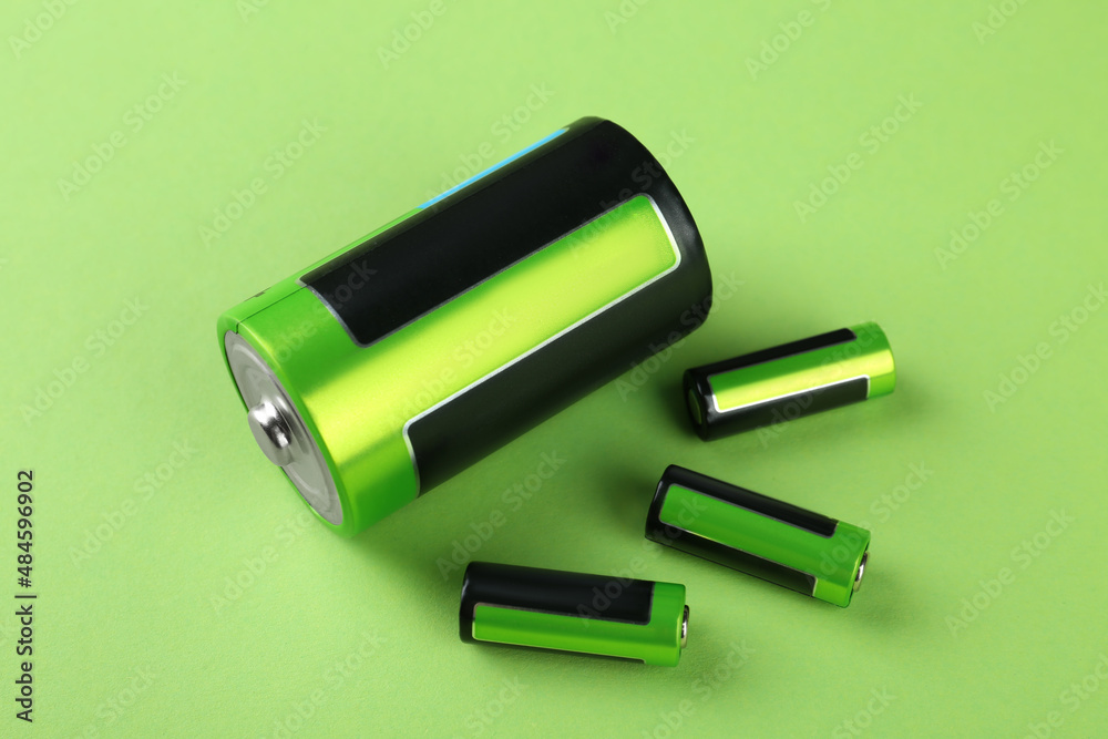 Different batteries on light green background, above view Different batteries on light green background, above view