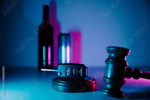 Car key, gavel and alcohol drinks in neon light. Dangerous driving and law photo