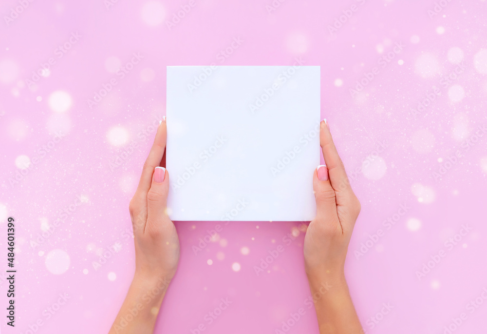 Obraz premium blank sheet of paper in female hands on a light pink background 