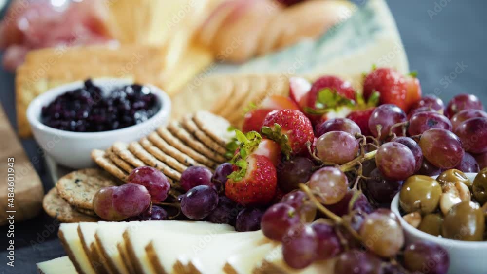 Arranging gourmet cheese, crakers, and fruits on a board for a large cheese board. Arranging gourmet cheese, crakers, and fruits on a board for a large cheese board.