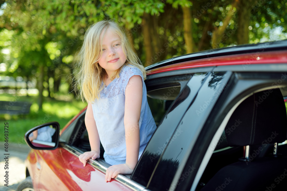 Funny young girl sticking her head out the car window looking forward for a roadtrip or travel.