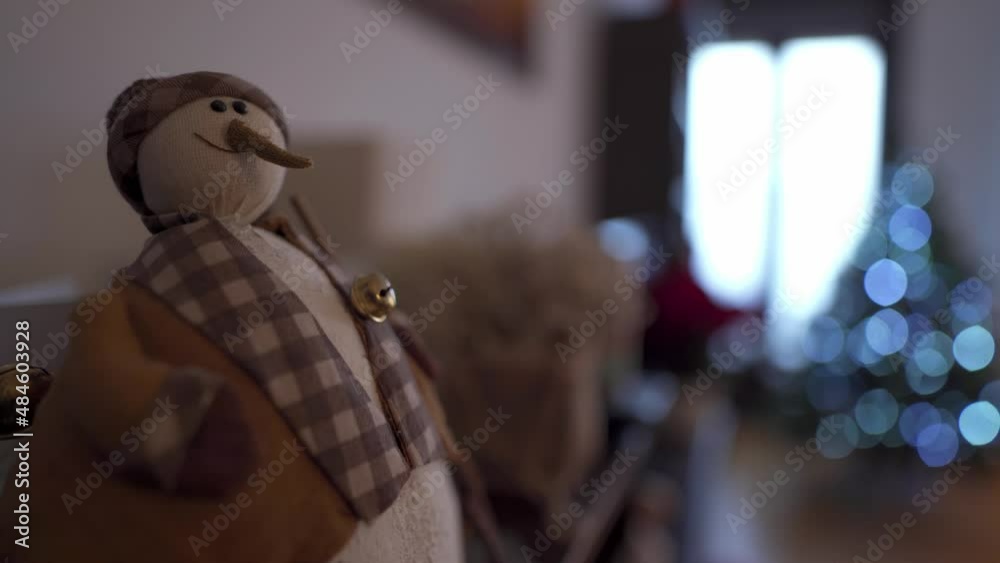 Snowman christmas decoration inside a home. Christmas tree out of focus on the background Snowman christmas decoration inside a home. Christmas tree out of focus on the background
