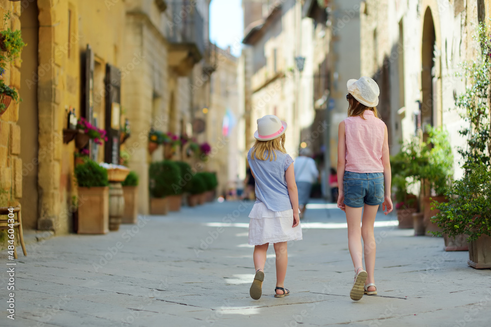 Young sisters exploring in Pienza, a village located in the beautiful Tuscany valley, known as the 'ideal city of the Renaissance' and a 'capital' of pecorino cheese.