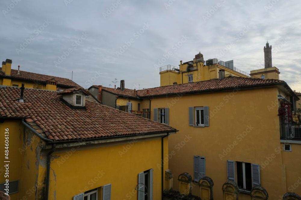 view of the red-tiled roofs of yellow houses and orange buildings in the town across the evening sky. City background. Italian architecture	