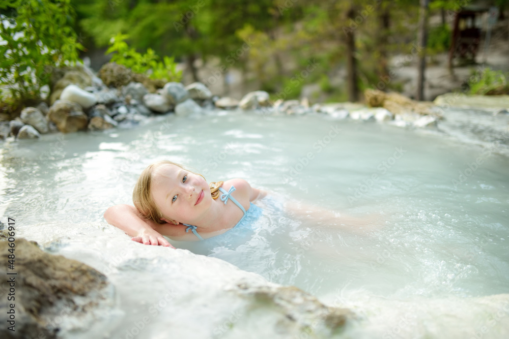 Young girl bathing in Bagni San Filippo, small hot spring containing calcium carbonate deposits, forming white concretions and waterfalls. Geothermal pools and hot springs in Tuscany, Italy. Young girl bathing in Bagni San Filippo, small hot spring containing calcium carbonate deposits, forming white concretions and waterfalls. Geothermal pools and hot springs in Tuscany, Italy.
